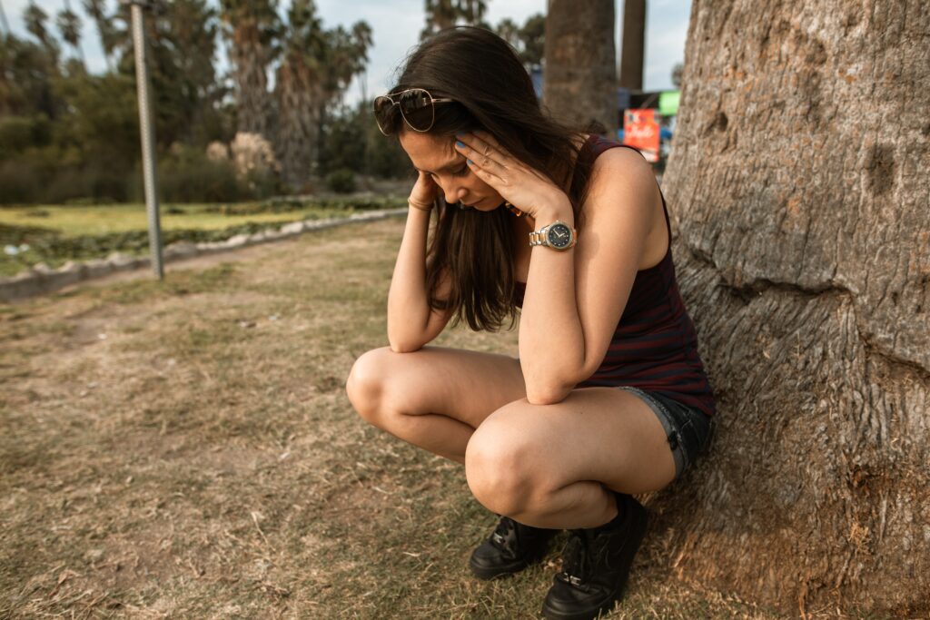 Femme stressée contre un arbre - Comment différencier le stress et l'anxiété ?