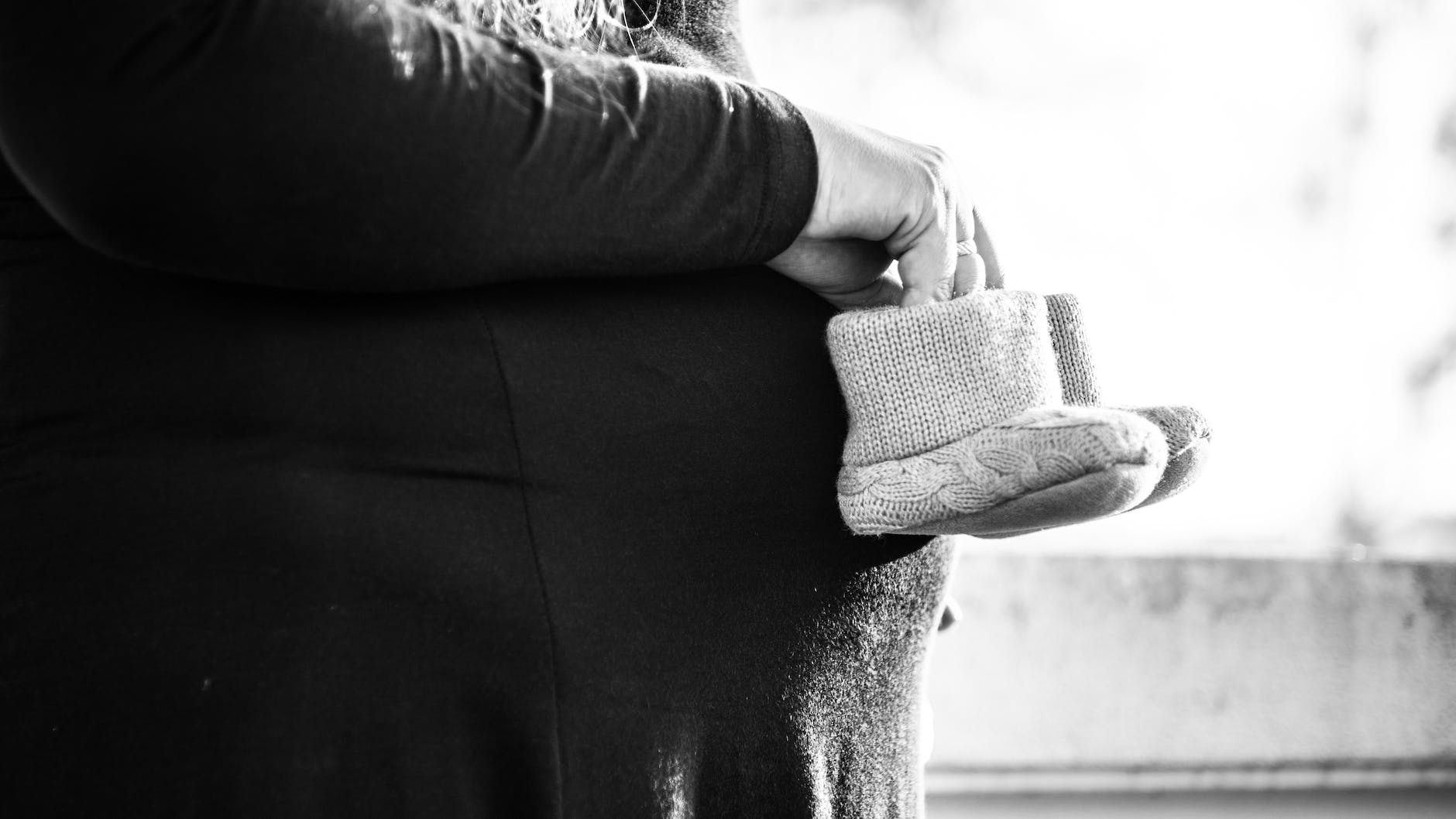 grayscale photo of person holding pair of toddler s shoes - Photo by Monika Balciuniene on Pexels.com